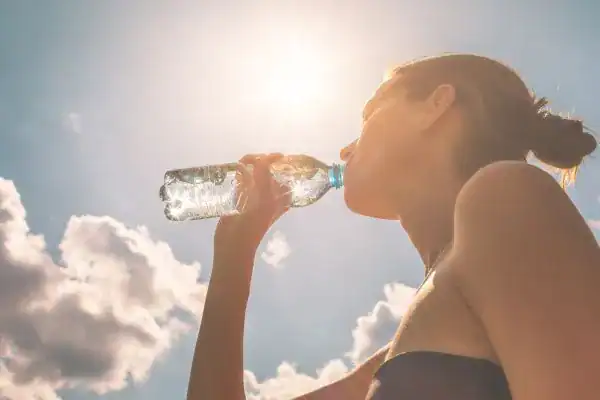 Hydration: The Secret Ingredient for a Toned Stomach and Enhanced Fitness 3 Image of woman drinking water to hydrate Sunbury Common after run.