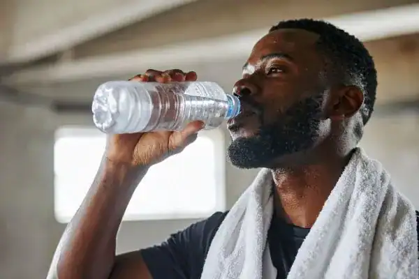 Hydration: The Secret Ingredient for a Toned Stomach and Enhanced Fitness 1 Image of man drinking water to improve hydration Sunbury Common after work out.